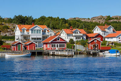 Houses by river and buildings against blue sky