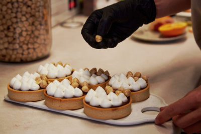 Confectioner is decorating a tarts with nuts in a cafe. french aesthetic hazelnut creamy tarts