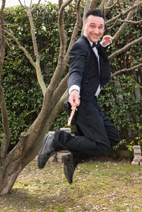 Portrait of happy man with flute jumping in park