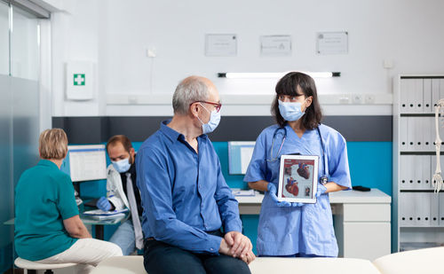 Doctor wearing mask showing heart to patient in clinic