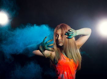 Young woman dancing against black background