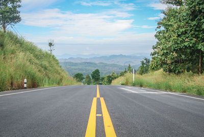 Road by trees against sky