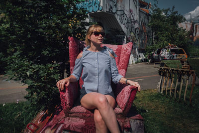 Young woman sitting on armchair against building