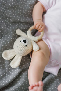 Soft knitted toy and a teether for teeth in the hands of a baby close-up person