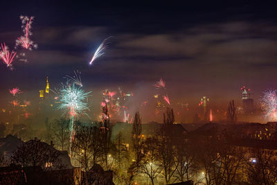 Firework display in city against sky at night