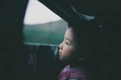 Close-up of cute girl looking through car window