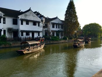 Boats moored in river with buildings in background