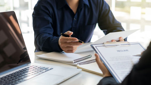 Midsection of man using mobile phone while sitting on table