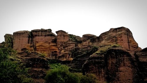 Low angle view of cliff against clear sky