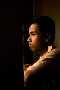 Side view of thoughtful boy standing by window