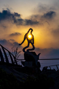 Low angle view of silhouette statue against sky during sunset