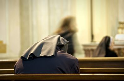 Rear view of nun praying at church