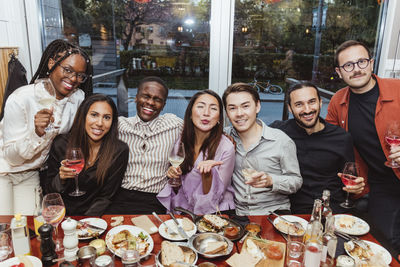 Cheerful multiracial female and male friends celebrating in bar afterwork