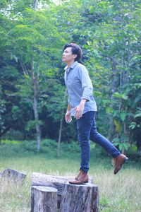 Full length of man looking away while standing against trees