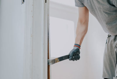 Hands of a man working with a crowbar indoors.