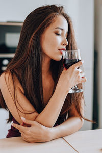 Beautiful young woman drinking water from while sitting outdoors