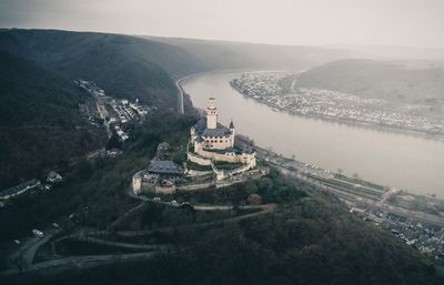 Aerial view of buildings by river in city against sky