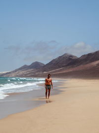 Rear view of boys on beach against sky