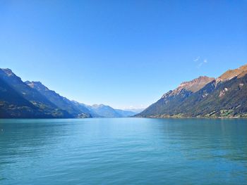 Scenic view of lake and mountains against clear blue sky