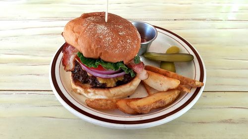 High angle view of burger by potato wedges in plate on wooden table