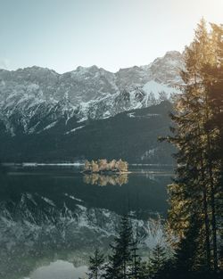 Scenic view of lake by snowcapped mountains against sky