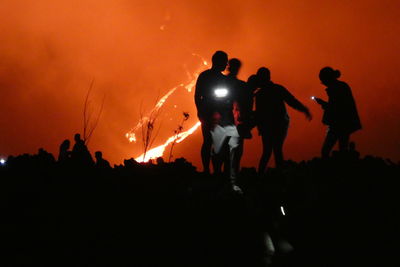 Silhouette people against fire at night