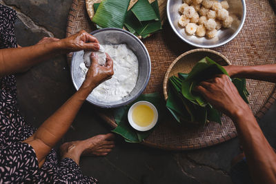 Low section of man and woman making rice cakes in cone