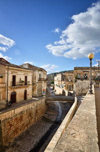 Footpath amidst buildings in town against sky