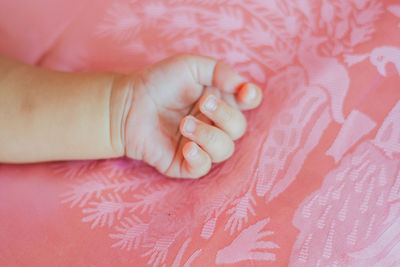 High angle view of baby hand on bed