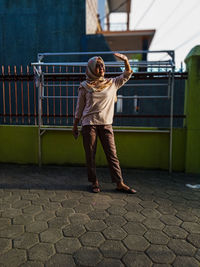 Full length rear view of woman standing on footpath