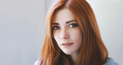 Indoor portrait of young woman with red hair and freckles