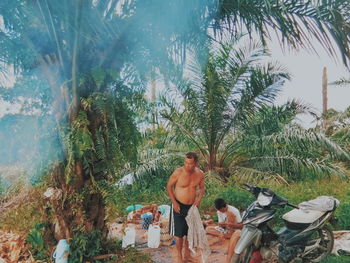 People standing by palm trees in forest
