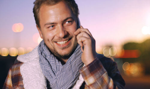 Close-up of smiling young man talking on mobile phone