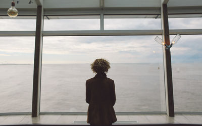 Rear view of woman standing on scheveningen pier at beach during sunset