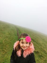 Portrait of girl standing on field during foggy weather