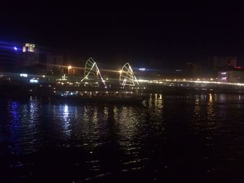 View of illuminated bridge over river at night