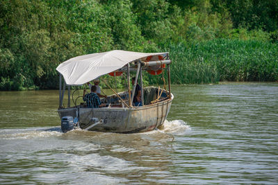 People in boat on river against trees