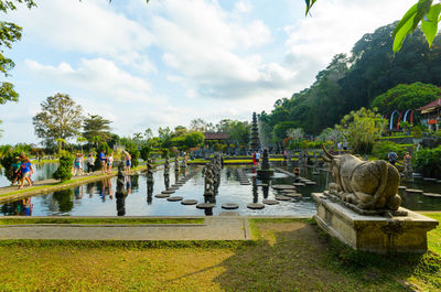 Group of people in park against cloudy sky