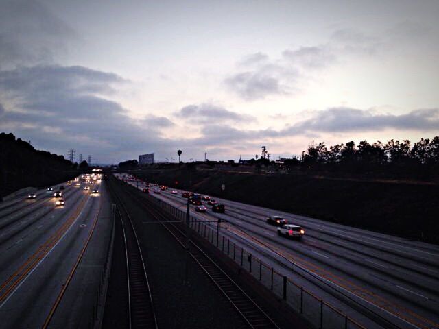 transportation, railroad track, rail transportation, the way forward, public transportation, mode of transport, sky, diminishing perspective, vanishing point, on the move, travel, cloud - sky, railroad station platform, railroad station, high angle view, road marking, road, journey, train - vehicle, highway