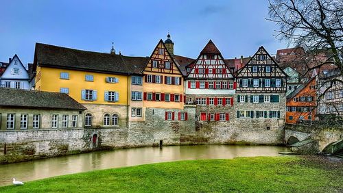 Houses by river against clear sky