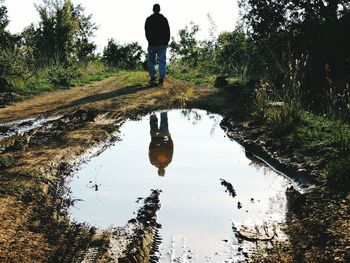 Reflection of man walking in puddle