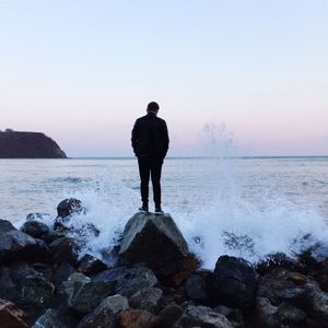 Rear view of man looking at breaking wave