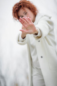 Close up focus on redhair woman is looking at camera and showing stop gesture