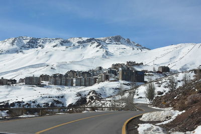 Snow covered road by snowcapped mountains against sky