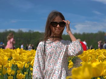 Young woman wearing sunglasses standing on field
