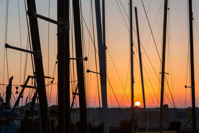 Silhouette of sailboats at harbor during sunset