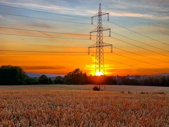 Electricity pylon on field against sky during sunset