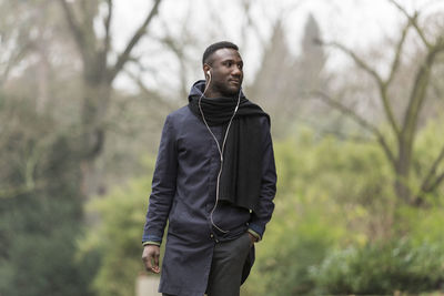 Man looking away while standing against trees