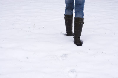 Low section of person walking on snow covered field