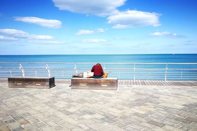 Couple by railing and sea against sky